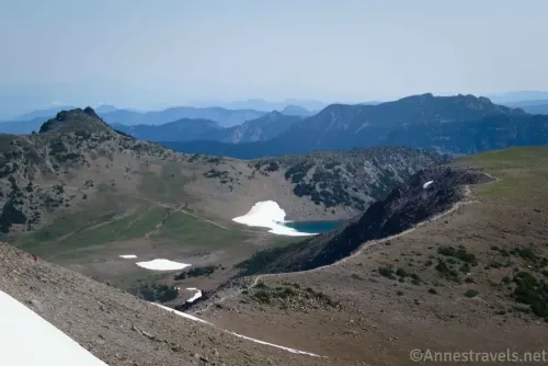 Frozen Lake in a bowl between meadows and distant mountains from Second Burroughs Mountain in Mount Rainier National Park 