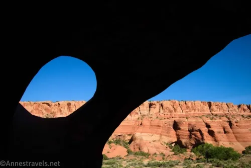A hole in a dark wall to striped rock cliffs