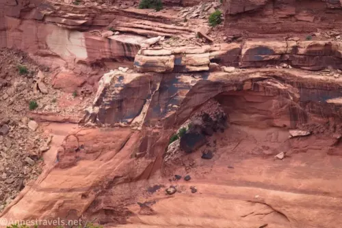 An arch on a canyon wall of red and black rock
