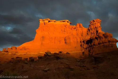 Sunset on a red butte in front of dark clouds