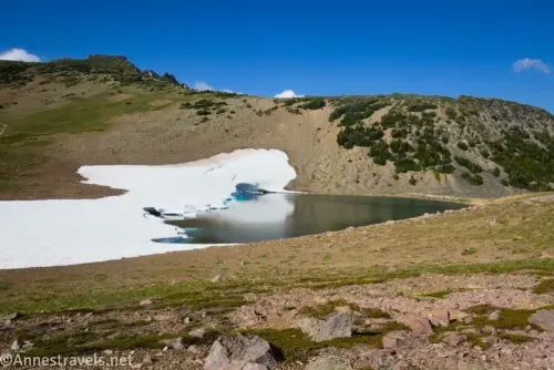 Frozen Lake with snow still on its left bank in meadows along the Sourdough Ridge Trail in Mount Rainier National Park