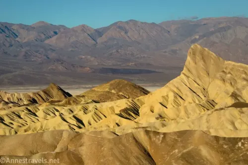 The triangular yellow badland called Manly Beacon with distant gray mountains from Zabriskie Point in Death Valley National Park 