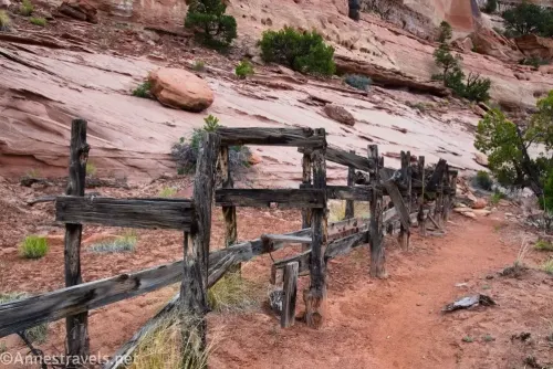 Wooden struts that once held a watering trough beside a dirt trail with nearby rocks 