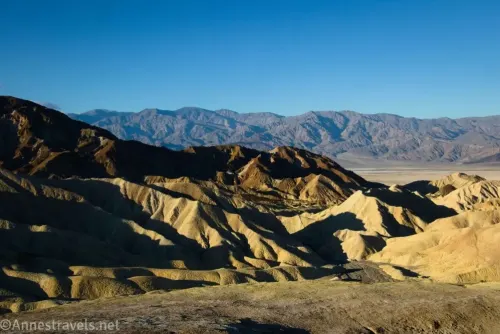 Early morning sun on the badlands and brown hills with gray mountains in the distance from Zabriskie Point in Death Valley National Park 