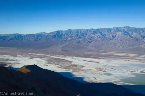 Views into a desert valley with a salt flat and distant mountains 