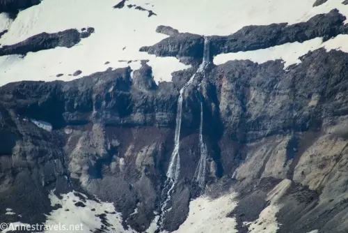 A waterfall on a rock wall falling from snowfields on Mount Rainier 