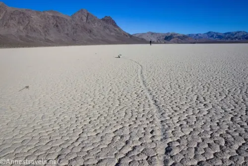 The dry lakebed Racetrack Playa with the line and rock of a sailing stone with mountains in the distance 