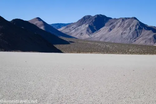 Mountains against the skyline across the white expanse of the Racetrack Playa lakebed 
