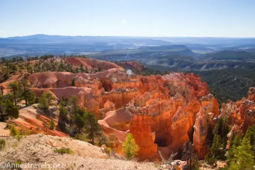 Broad and sweeping views across hoodoos, pink hills, and green hills in Bryce Canyon National Park along the Under the Rim Trail on the way to the Hat Shop, Utah