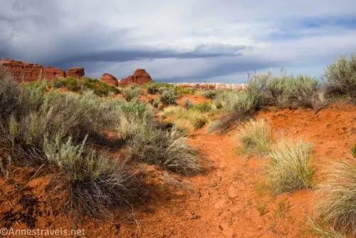 Clouds over the desert including footprints in a wash on the way to Blocked Arch in Arches National Park, Utah