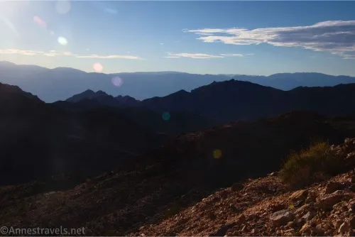 Blue and shadowed mountains against a blue sky with a few white clouds 