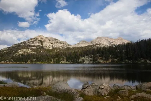 Mountains across a lake with small reflections and clouds in the sky