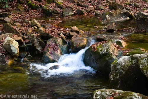 A waterfall between large rocks in a stream