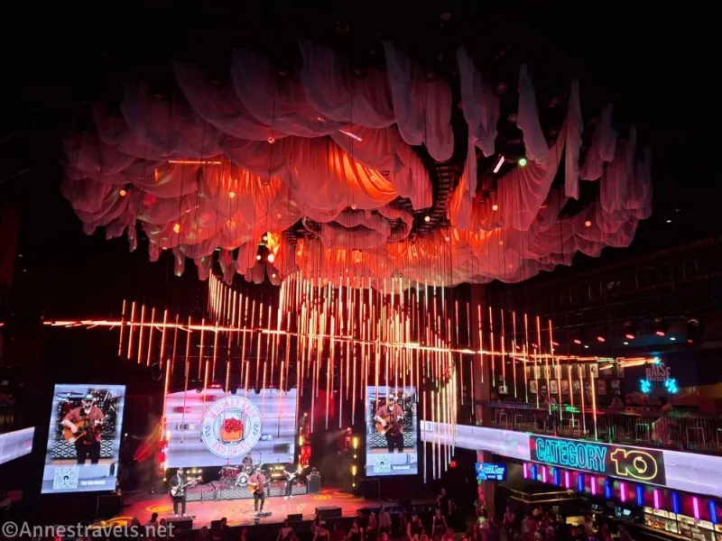 White curtains with red lights on the ceiling, a band on a stage, and a sign that says Category 10
