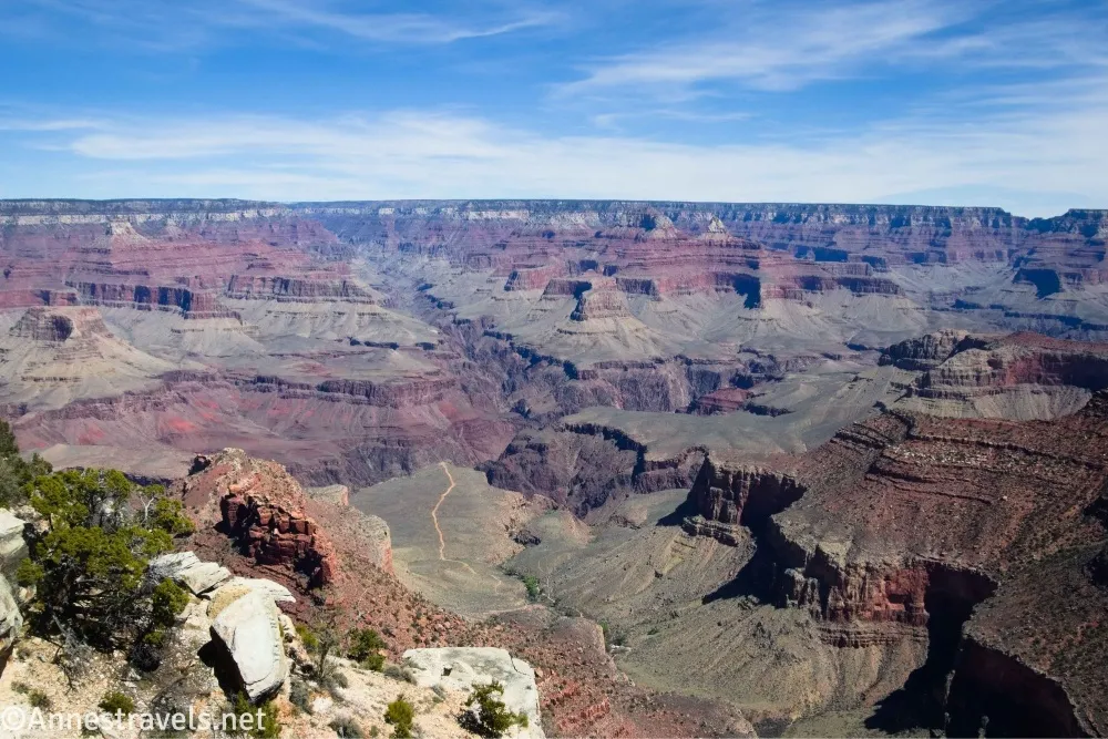 The Grand Canyon including canyons and buttes below clouds in a blue sky