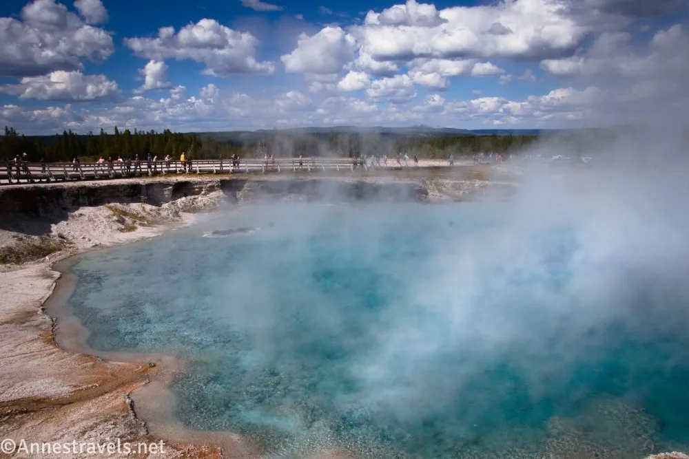 Clouds over a boardwalk and the steaming blue water of Excelsior Geyser in the Midway Geyser Basin of Yellowstone National Park