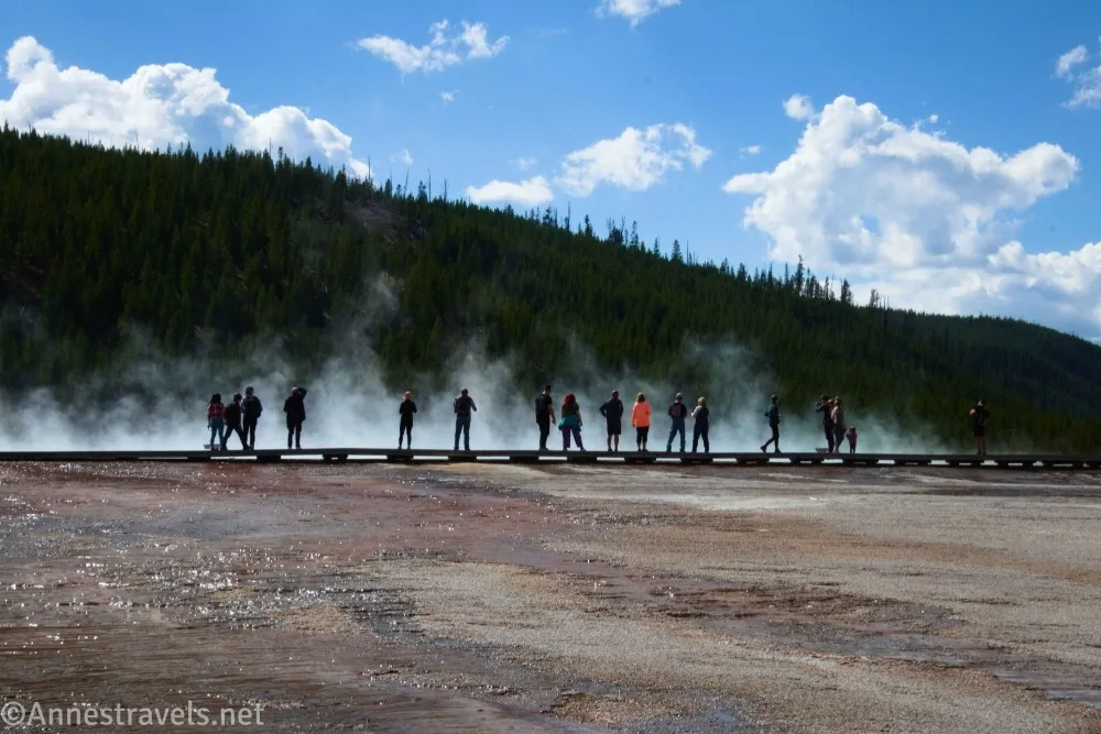People on a boardwalk in front of steam clouds from the Grand Prismatic Spring, Midway Geyser Basin in Yellowstone National Park