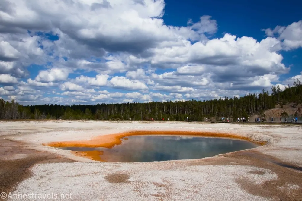 Clouds sail over an orange-ringed hot spring called Turquoise Pool in the Midway Geyser Basin of Yellowstone National Park