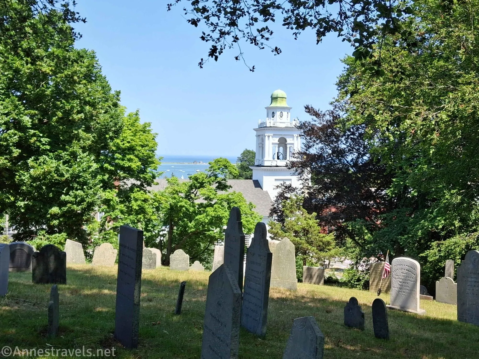 Gravestones on Burial Hill overlooking a church and Plymouth Harbor in Massachusetts
