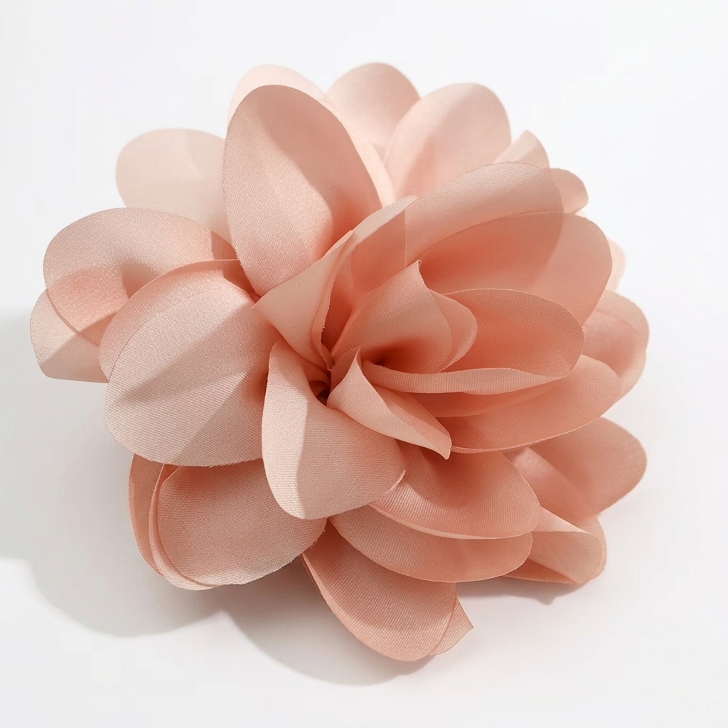 An artificial peach-colored fabric flower with layered petals on a white background.
