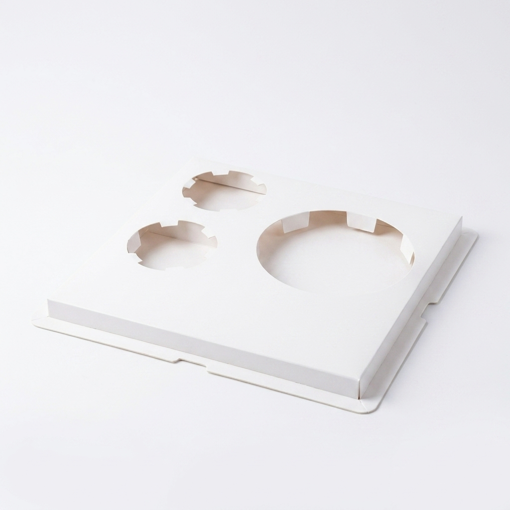 A white cardboard gift box insert with die-cut circular compartments on a seamless background.