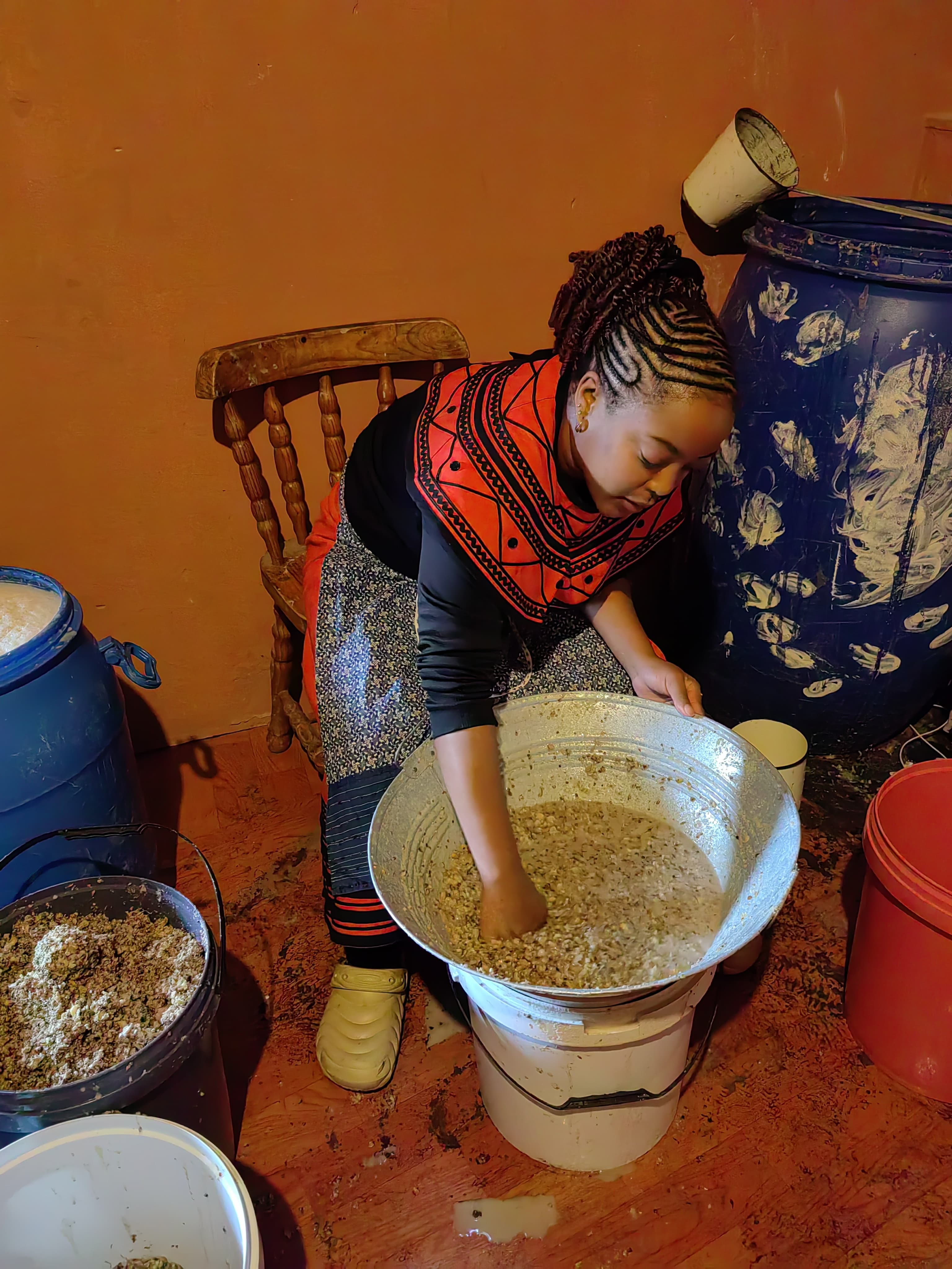 Brewing umqombothi in a red-and-black Xhosa beaded collar