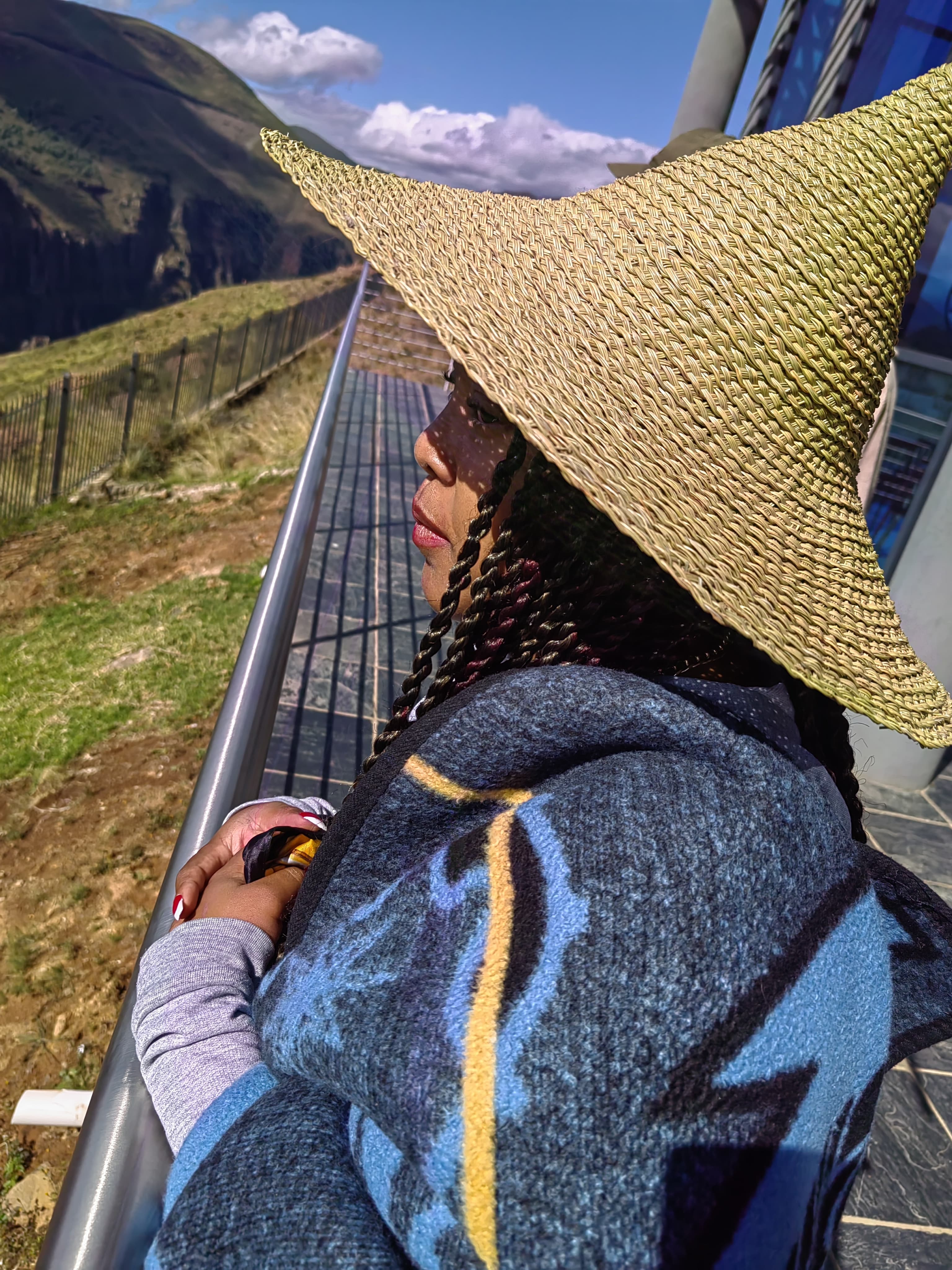 Wrapped in a Basotho blanket and grass hat, mountain beyond