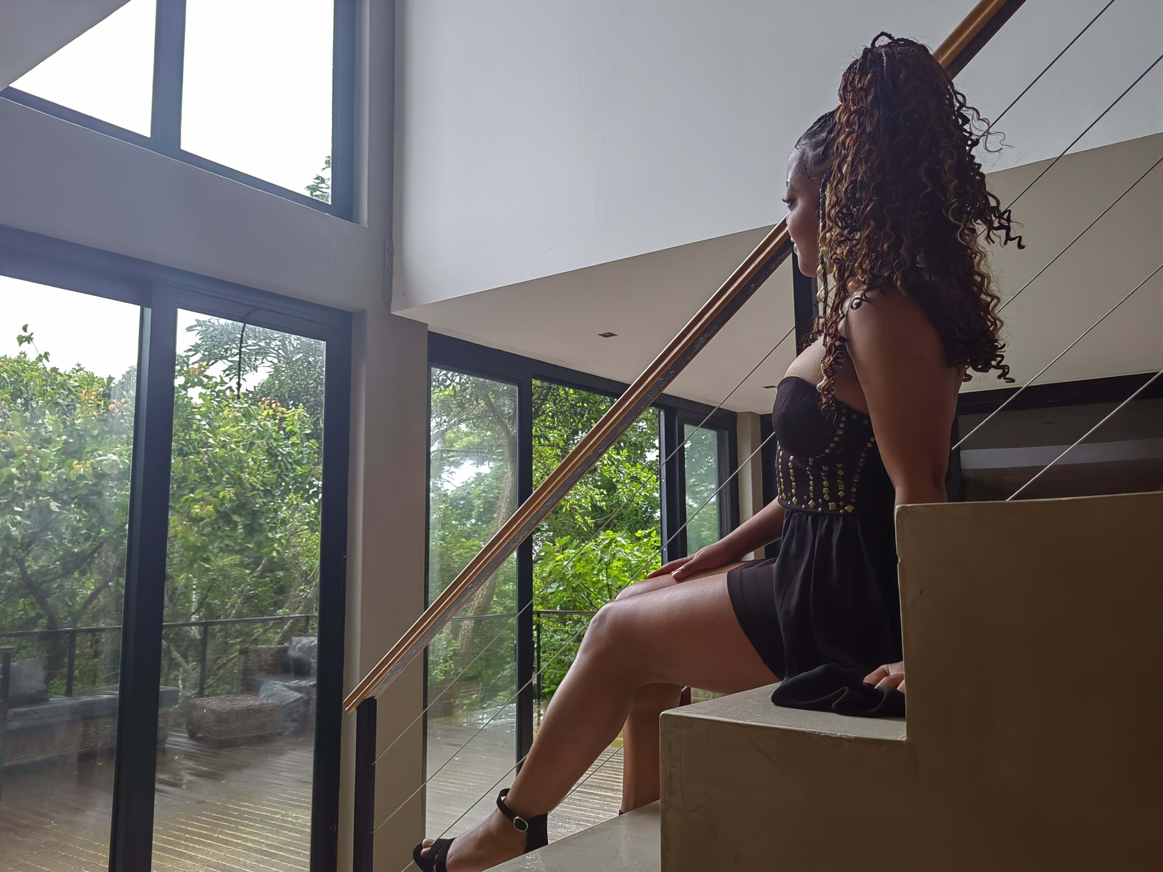 Seated on the stairs by a glass wall, pensive