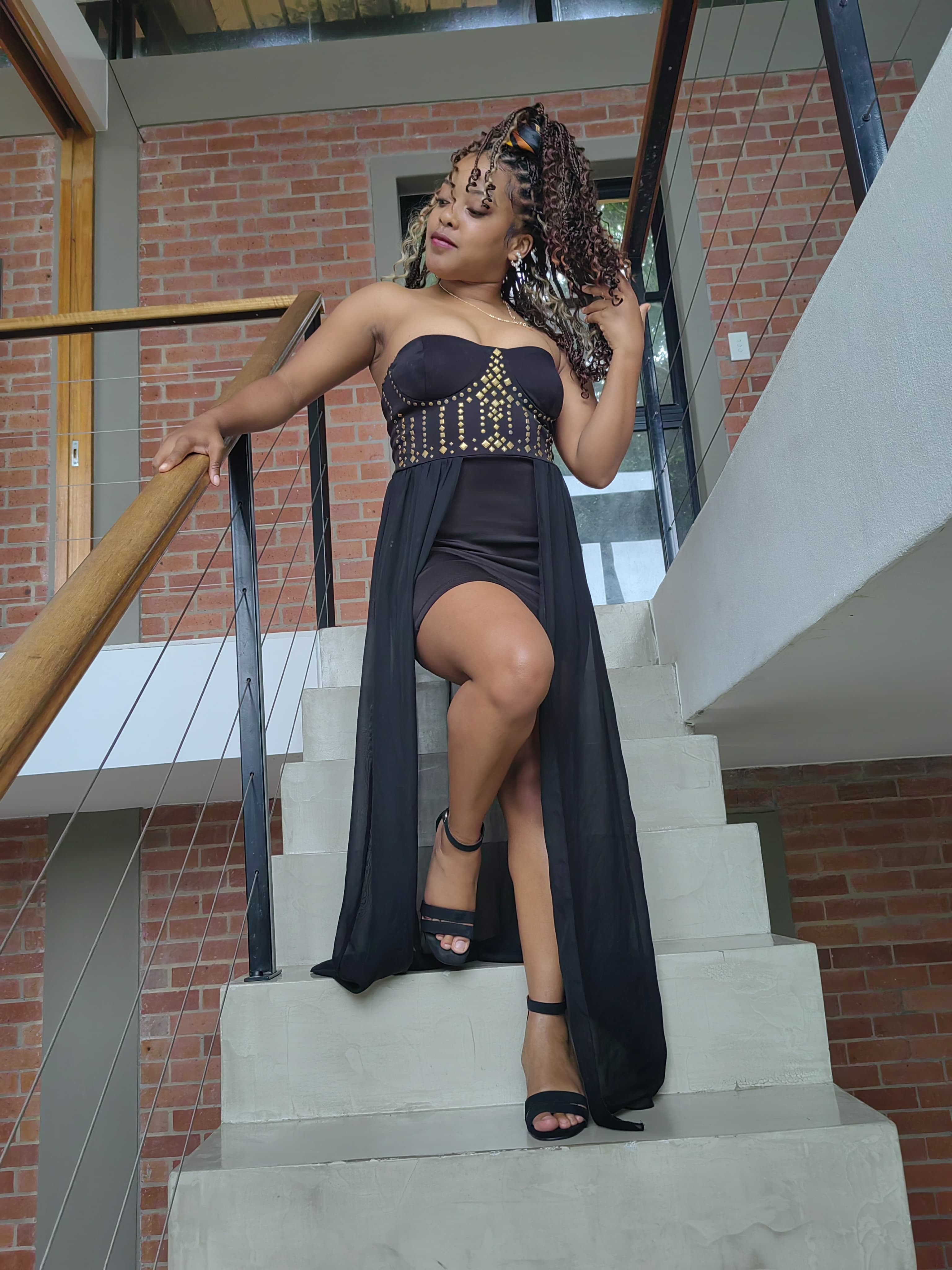 A commanding pose, hand on the staircase rail