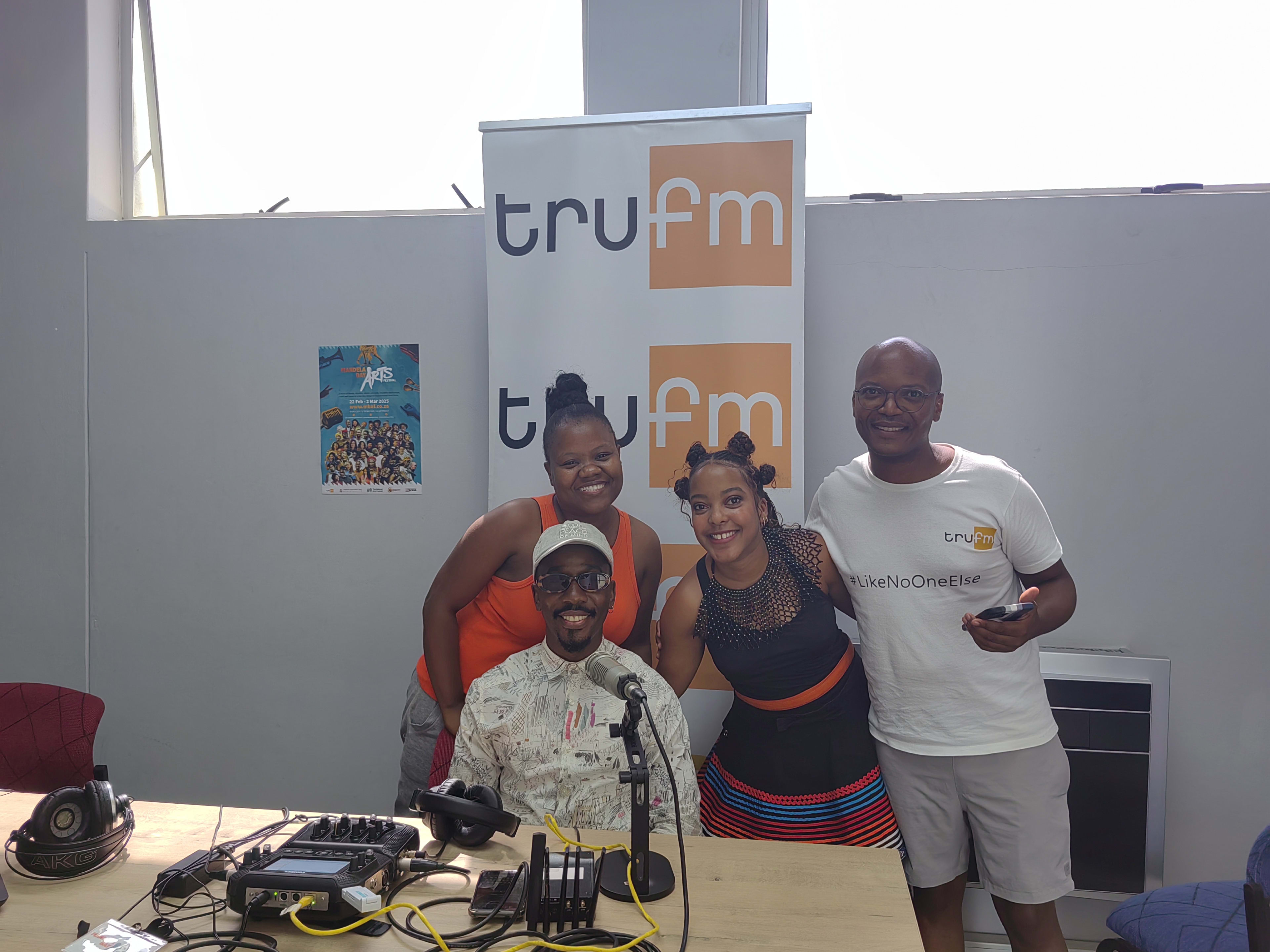 A group beneath the TRU FM backdrop