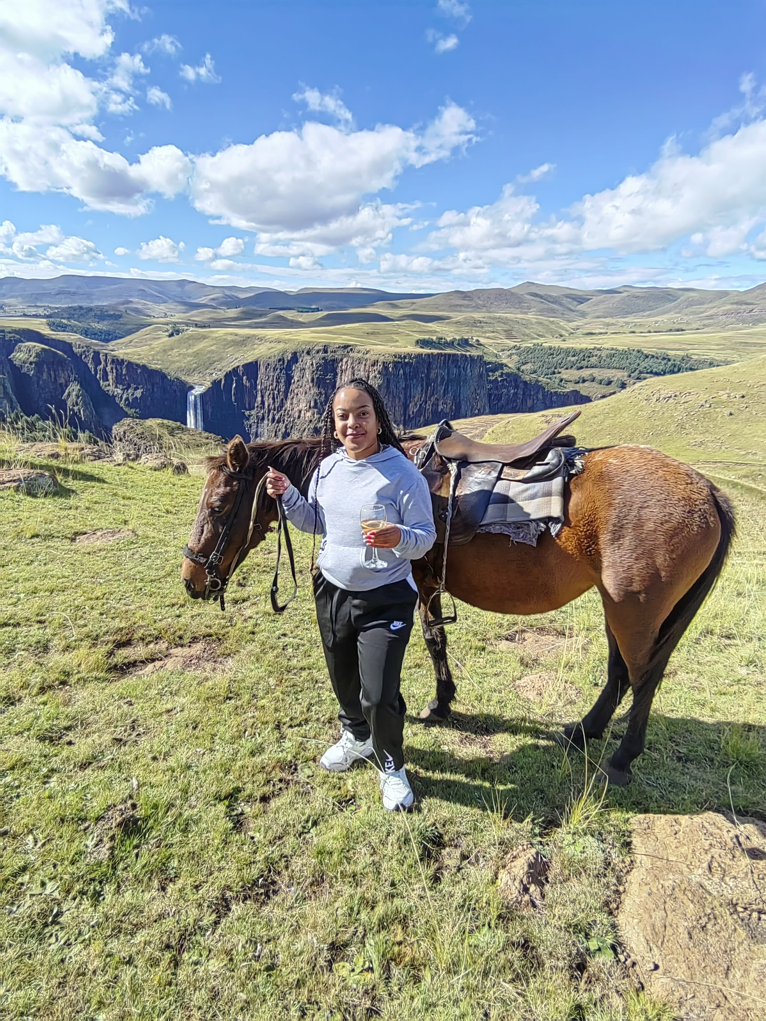 Holding a horse by the reins on a green plateau