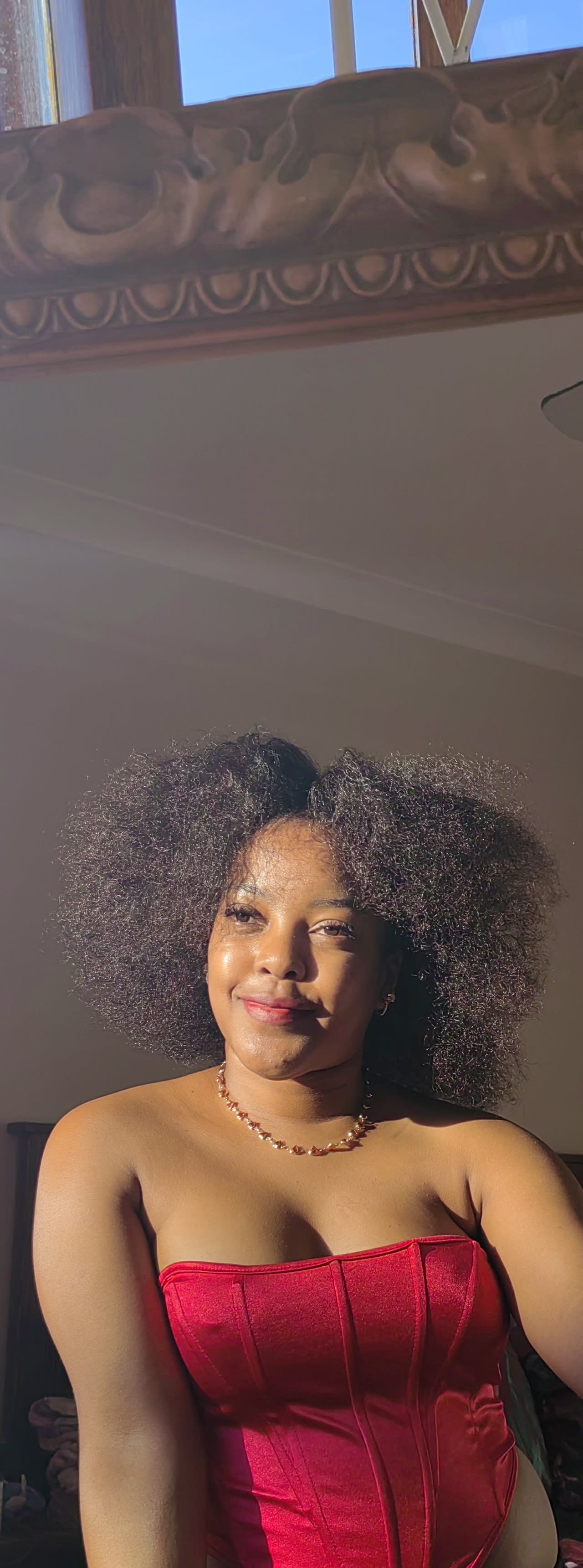 Nandawula Regine — natural afro haloed in golden light, red satin bodice