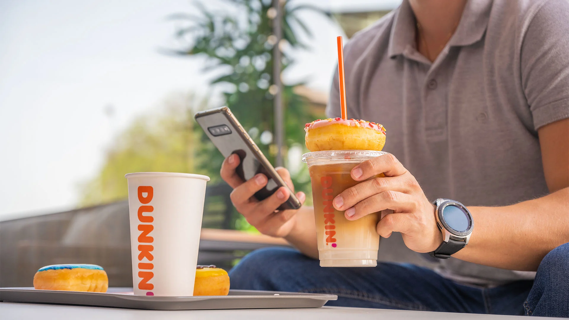 A man enjoying some coffee and donuts from Dunkin'.