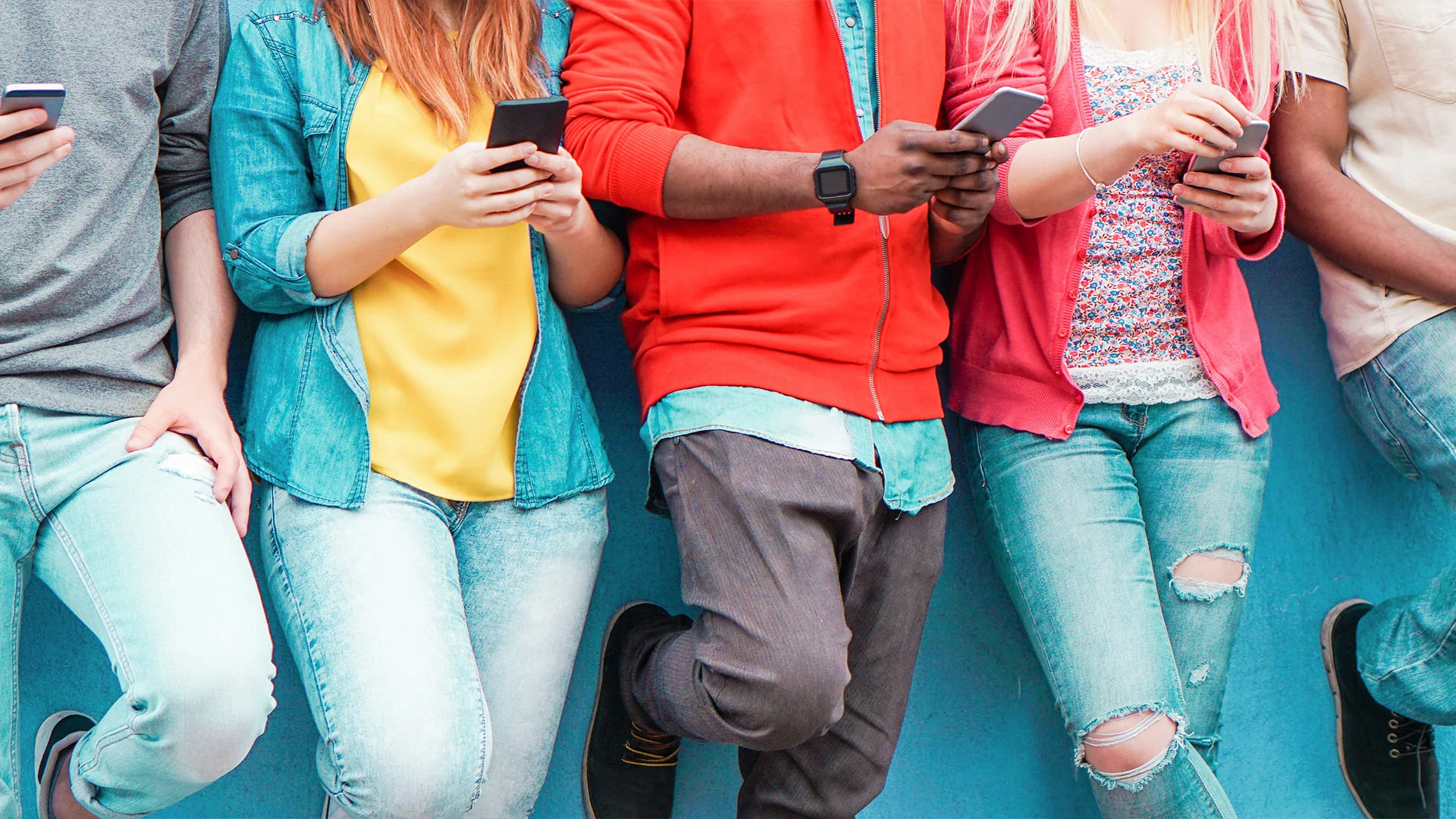 A group of people standing shoulder to shoulder while using mobile devices.