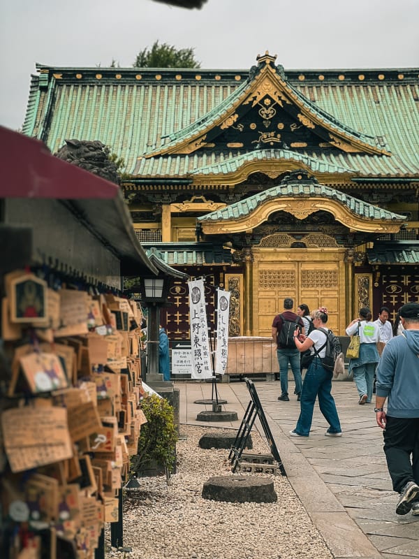 Ueno Toshogu Shrine, Tokyo, Japan. Grand golden temple, green copper roof, ornate carvings, bustling visitors, ema wall.