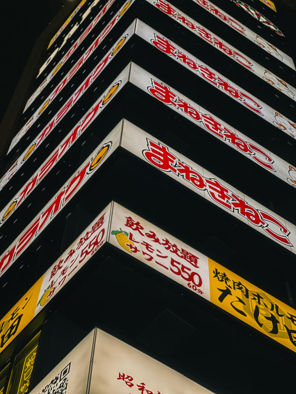 Manekineko Karaoke building signs, red Japanese script, glowing lemon sour ad, vibrant Shinjuku, Tokyo night.