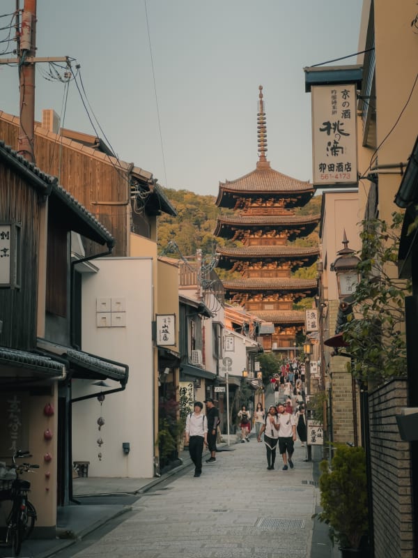 Yasaka Pagoda, Kyoto, Japan, towering over a historic Sannenzaka street filled with tourists and traditional wooden buildings.