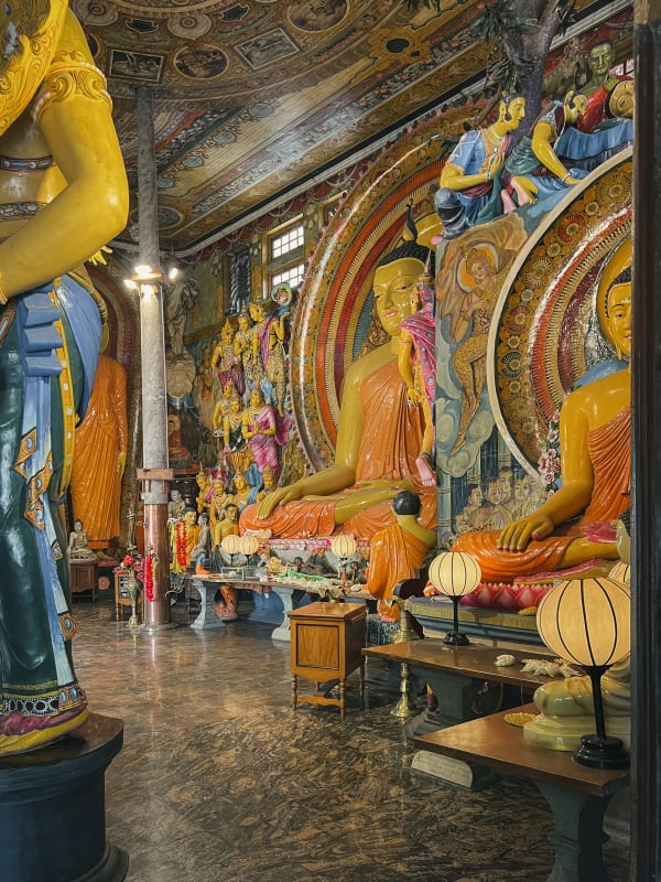 Ornate Buddha statues & vibrant murals inside Gangaramaya Temple, Colombo, Sri Lanka. Intricate Buddhist artwork.