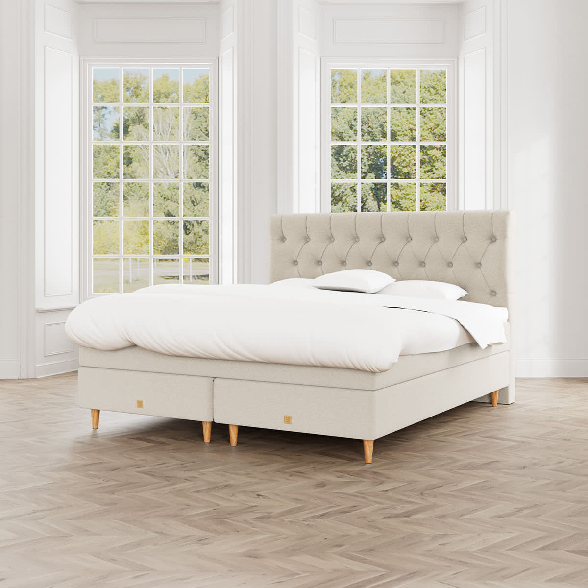 Beige kontinentalseng Nova fra MasterBed Select med polstret sengegavl og ben i eg.