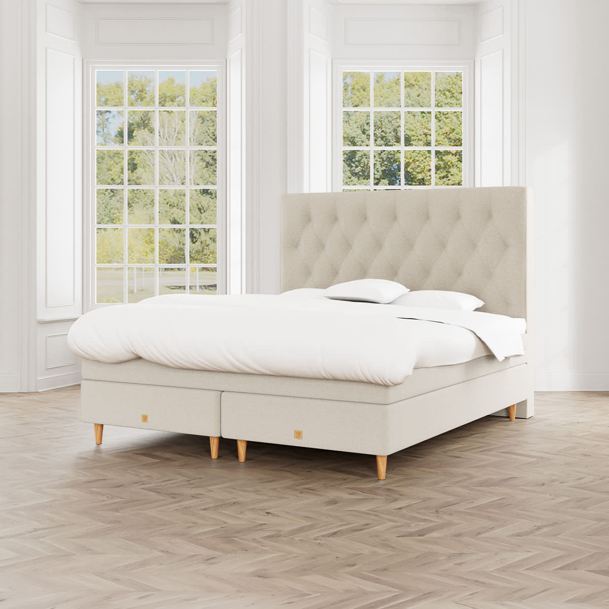 Beige MasterBed Select kontinentalseng Nova med polstret gavl i felter og ben i eg.