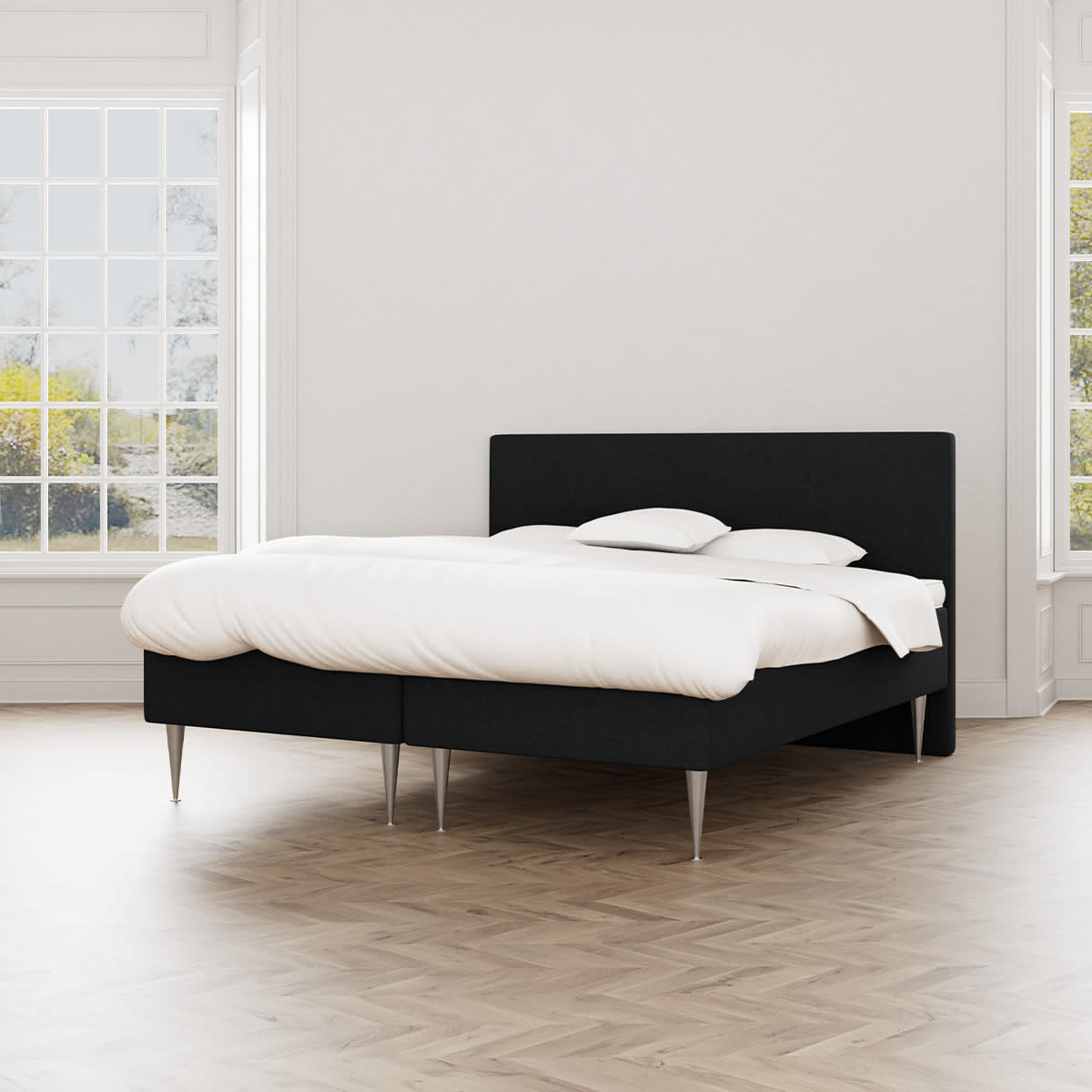 Sort boxmadras Sleepy fra MasterBed Standard med hvidt sengetøj og cocktailben, set forfra.