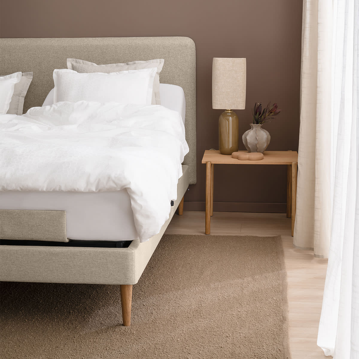 Beige seng fra TEMPUR i modellen Move med hvid madras og polstret bund, set fra siden.