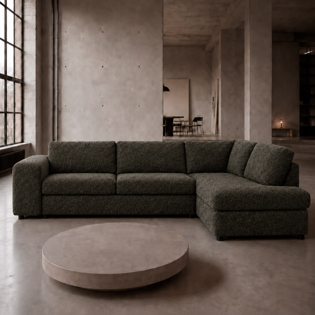 Mørk mosgrøn hjørnesovesofa Vigga i bouclé i industriel stue med betonvægge og lavt rundt bord.