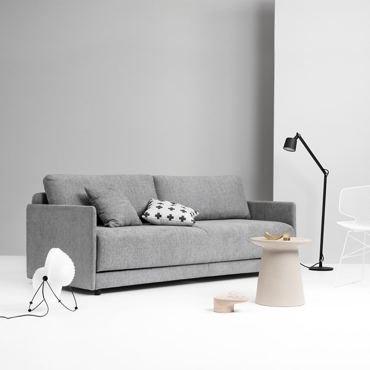 Moderne stue med grå sofa, et rundt sidebord og designerlamper. Minimalistisk interiør i grå og hvide toner.