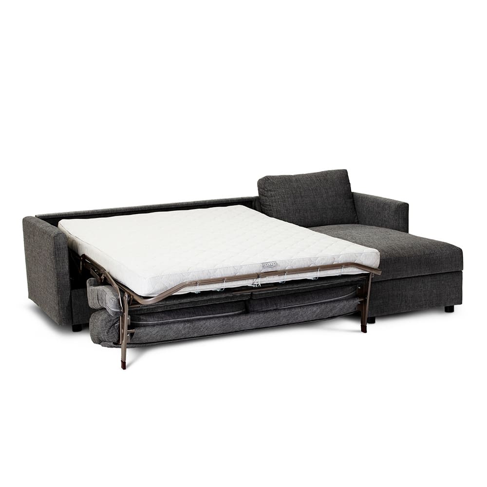 Mørkegrå hjørnesofa med udslået seng og en hvid madras.