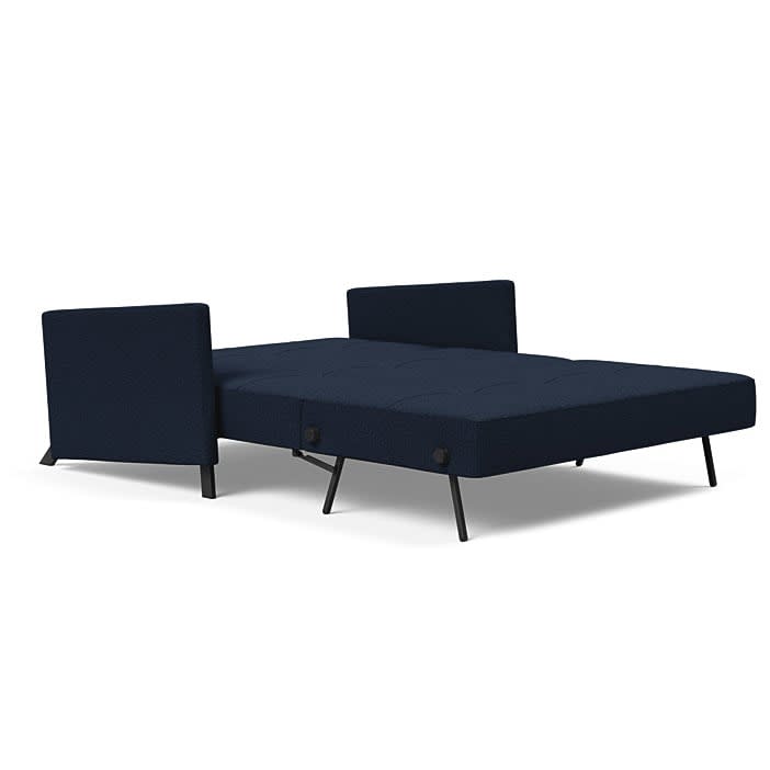 Marineblå sovesofa udfoldet til seng med sorte ben.