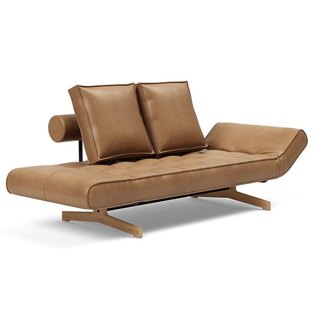 En moderne lysebrun læder daybed med to puder og en rund nakkepude på træben.