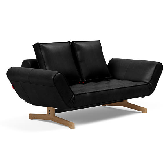 Moderne sort daybed med quiltet sæde, løse puder og lyst træstel.