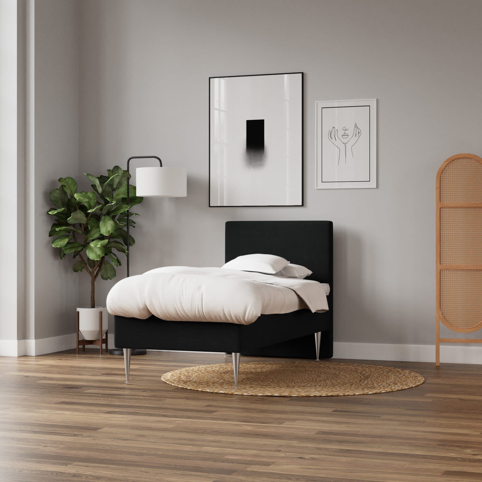 Minimalistisk soveværelse med sort seng, hvidt sengetøj og trægulv. To kunstplakater på grå væg.