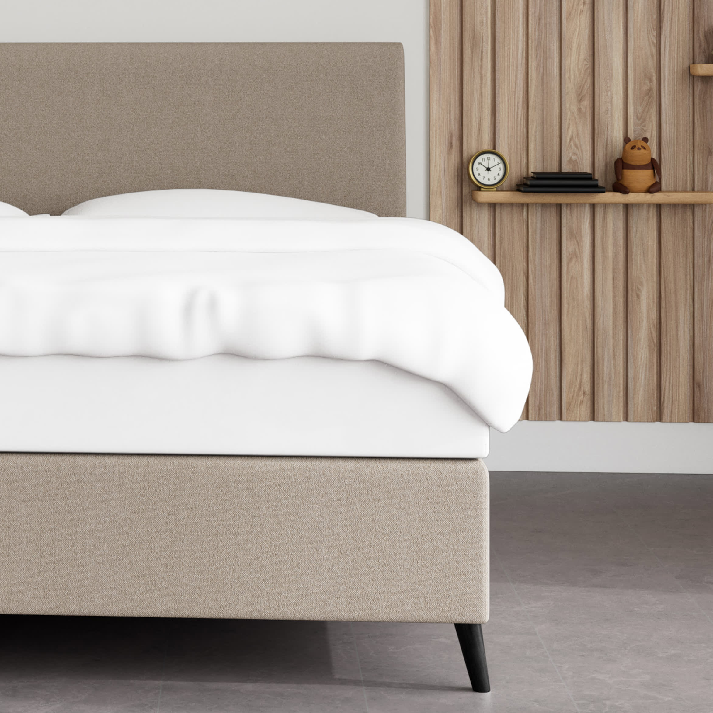 En seng med sandfarvet gavl og hvid dyne. En væg med træpaneler, hylde, ur og tøjdyr.